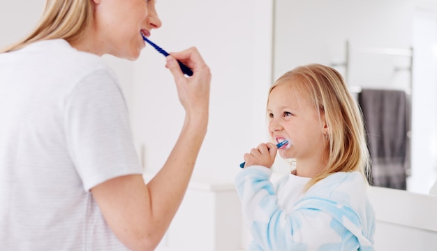 Entwicklung Mutter und Mädchen im Badezimmer mit Zahnbürste, die Bindung umarmen und zusammen lieben Weibliche Eltern Dame und Kind oder Kind putzen Zähne Zahnhygiene und Wachstum des Kindes zu Hause