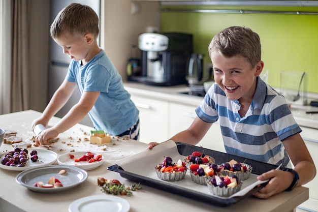 Entzückende Babykinder kochen hausgemachtes süßes Dessert in der Küche und servieren frisches Obst und Beeren