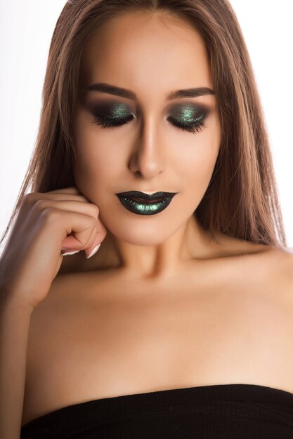 Entzückende brünette Frau mit perfekter Haut und kreativem metallisch-grünem Make-up. Nahaufnahmeporträt im Studio auf einem weißen Hintergrund