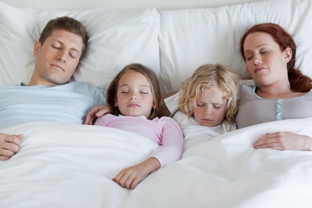 Foto entzückende familie, die zusammen im bett schläft