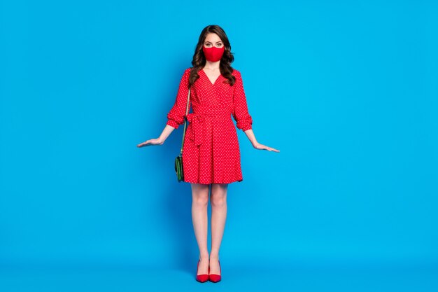 entzückende junge brünette Dame im roten Minikleid trägt medizinische Maske posiert