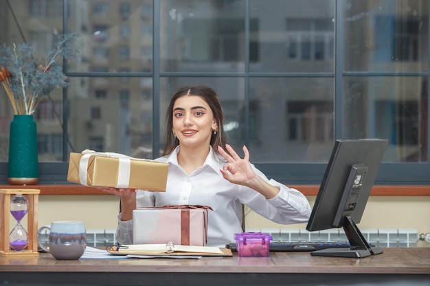 Entzückende junge Holding verpackte Geschenkbox und Händeschütteln Hochwertiges Foto