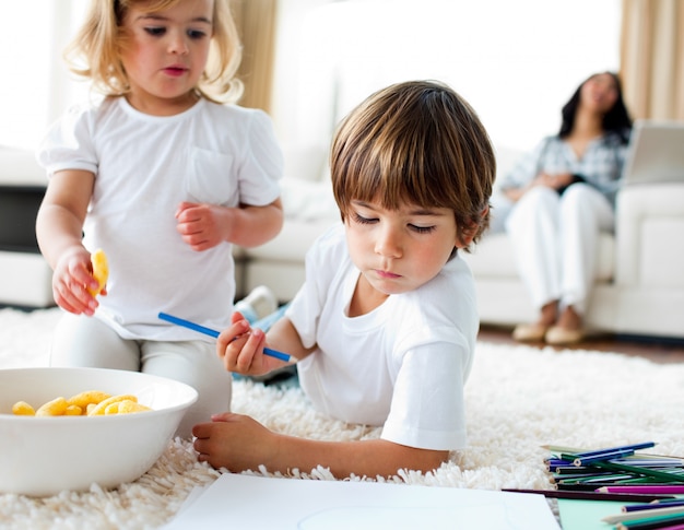 Entzückende Kinder, die Chips essen und zeichnen