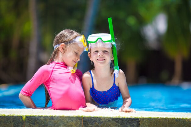 Entzückende kleine Mädchen an der Maske und an den Schutzbrillen im Swimmingpool im Freien