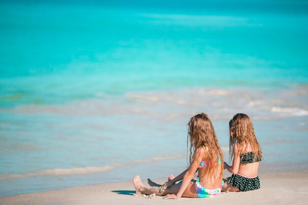 Entzückende kleine Mädchen, die auf dem Strand sich entspannen