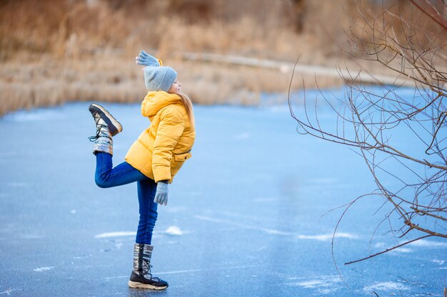 Entzückende kleine Mädchen, die auf die Eisbahn eislaufen