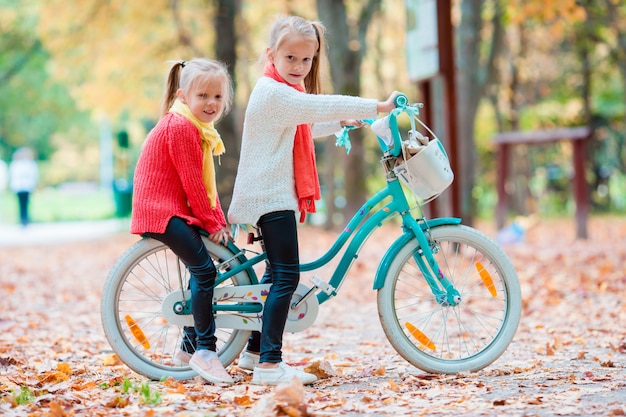 Entzückende kleine Mädchen, die draußen ein Fahrrad am schönen Herbsttag fahren