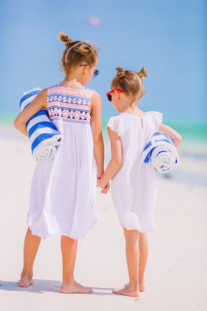 Entzückende kleine Mädchen mit Strandtüchern am weißen tropischen Strand