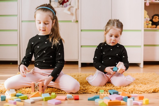 Entzückende kleine Mädchen spielen zu Hause mit farbigen Blöcken