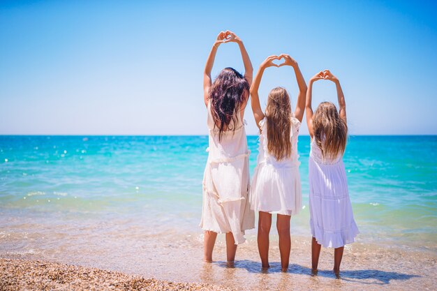 Entzückende kleine Mädchen und junge Mutter am tropischen weißen Strand