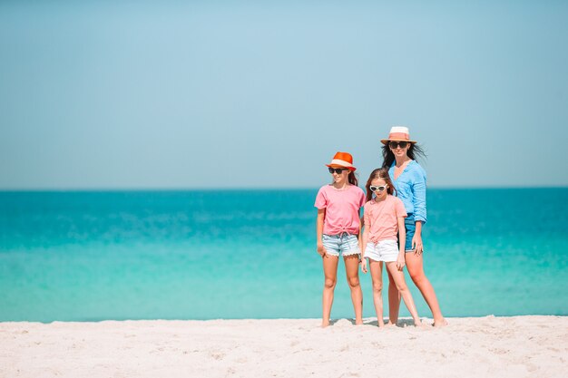 Entzückende kleine Mädchen und junge Mutter am weißen Strand