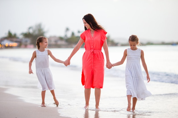 Entzückende kleine Mädchen und junge Mutter auf weißem Strand