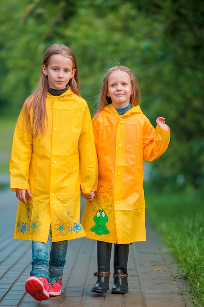 Entzückende kleine mädchen unter dem regen am warmen herbsttag