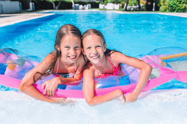 Entzückende kleine Schwestern spielen im Swimmingpool im Freien