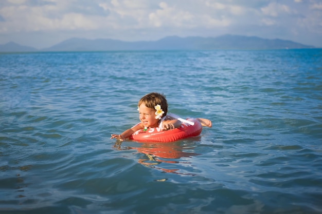 Entzückende Kleinkinder schwimmen im Meer in einem speziellen aufblasbaren Rettungsring