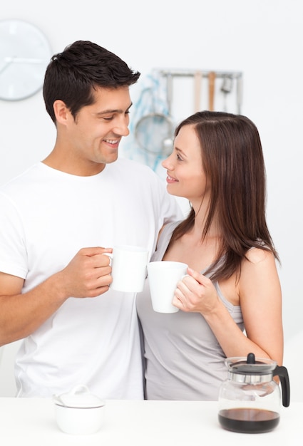 Entzückende Paare, die Tasse Kaffee halten und einander Frühstück betrachten