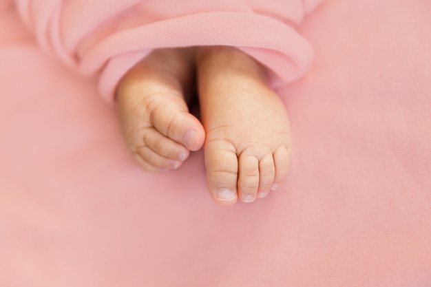 Entzückende Zinkenbaby-Mädchenfüße auf weichem rosa Oberflächen-, Mutterschafts- und Kindheitskonzept