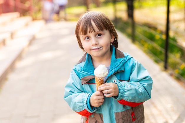 Entzückender Junge, der bei sonnigem Frühlingswetter Softeis im Freien isst Lächelndes Kind in einem Park mit süßem Dessert