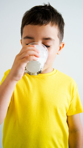 Entzückender Junge mit Glas Milch oder Kefir auf weißem Hintergrund