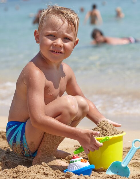 Entzückender Junge spielen am Strand mit Sand