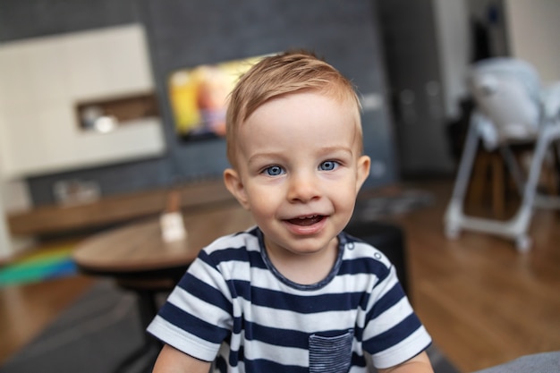 Entzückender kleiner Junge mit schönen blauen Augen, die zu Hause aufwerfen.