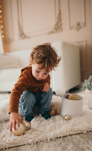 Entzückender Kleinkindjunge, der mit Weihnachtsbällen spielt