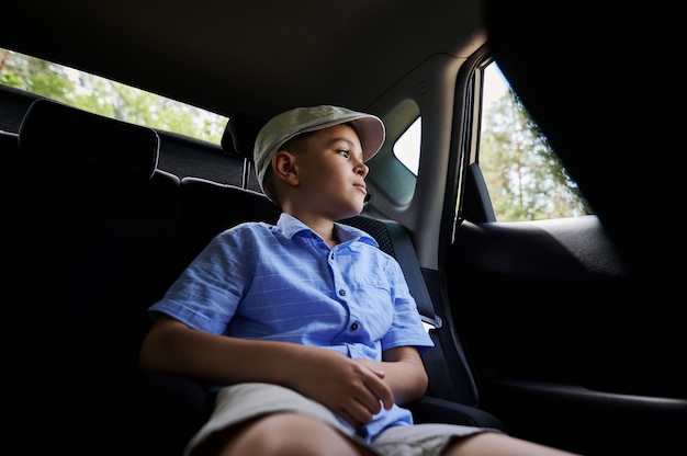 Entzückender Teenager, der im hinteren Beifahrersitz sitzt und aus dem Fenster schaut