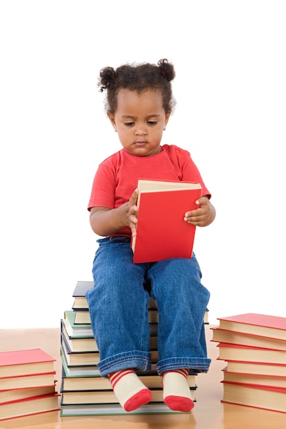 Entzückendes afrikanisches Babylesen, das auf einem Stapel der Bücher auf einem over white Background sitzt