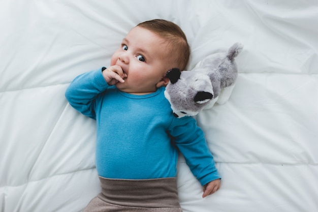 Entzückendes Baby, das an seiner Hand lutscht