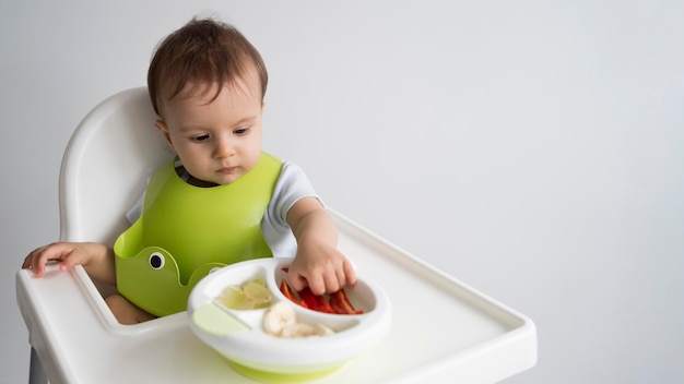 Foto entzückendes baby, das mit essen spielt