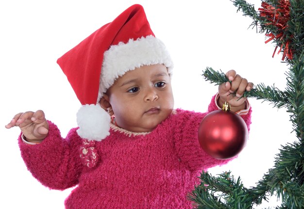 Entzückendes Baby, das mit Weihnachtsbaum über weißem Hintergrund spielt