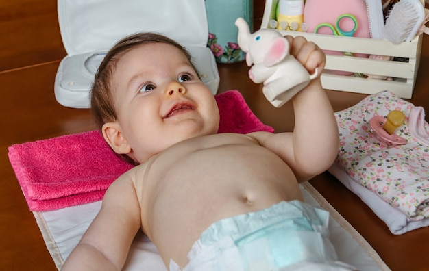 Entzückendes Baby, das nach dem Windelwechsel mit einem Gummispielzeug für Kinder spielt