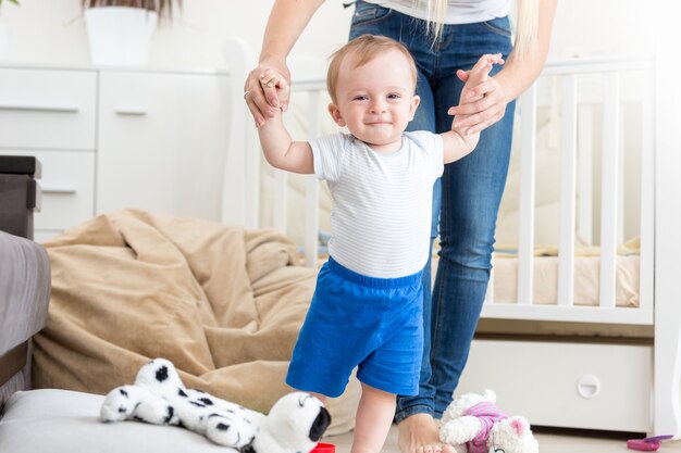 Entzückendes Baby, das zu Hause mit der Mutter das Gehen lernt