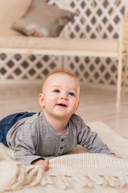 Entzückendes Baby im sonnigen Schlafzimmer. Neugeborenes Kind entspannt. Familienmorgen zu Hause. Neugeborenes Kind während der Bauchzeit.