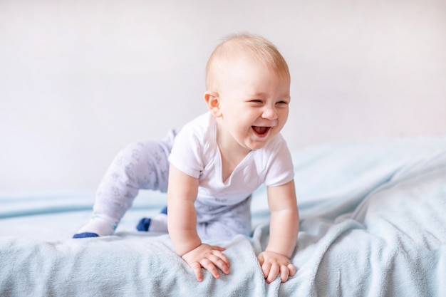 Entzückendes Baby im weißen sonnigen Schlafzimmer. Neugeborenes Kind, das auf einem blauen Bett sich entspannt. Kindergarten für kleine Kinder.