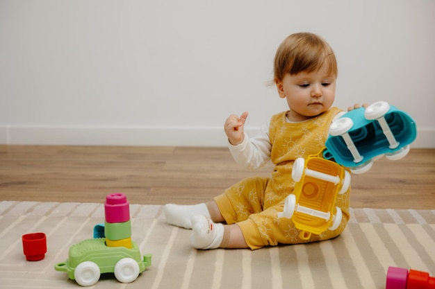 Entzückendes Baby mit blonden Haaren, das mit Spielzeug spielt