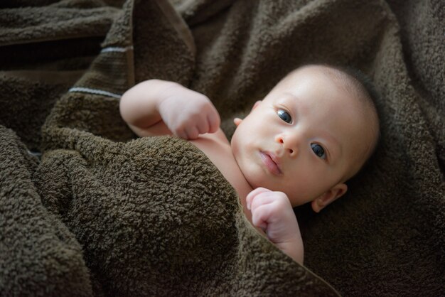 Entzückendes Baby unter einem mit Kapuze Tuch nach Bad