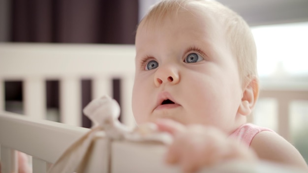 Entzückendes Babygesicht im weißen Kinderbett. Schönes Kind im Bett. Schönes Säuglingsgesicht