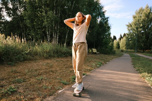 Entzückendes glückliches Mädchen, das Skateboard im Park reitet