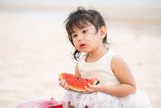 Entzückendes Kind, das Wassermelone auf dem Strand isst.