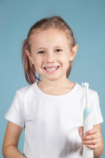 Entzückendes kleines kaukasisches Kind, das Zahnbürste auf blauem Hintergrund hält, Hygienekonzept