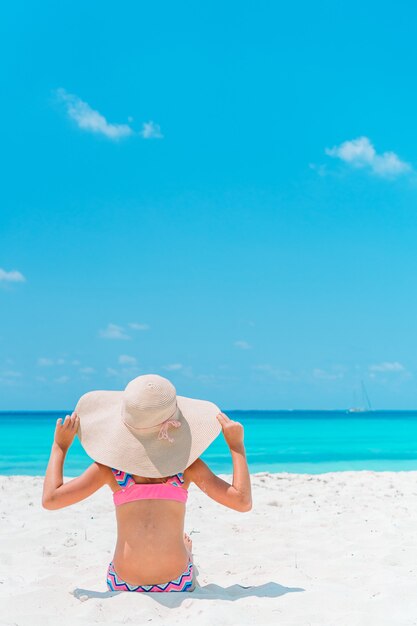 Entzückendes kleines Mädchen am Strand. Glückliches Mädchen genießen Sommerferien den blauen Himmel und das türkisfarbene Wasser im Meer