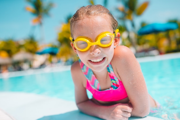 Entzückendes kleines Mädchen, das am Außenschwimmbad schwimmt