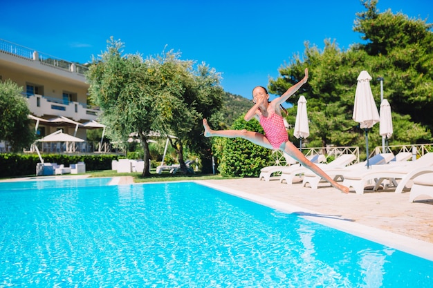 Entzückendes kleines Mädchen, das am Außenschwimmbad schwimmt