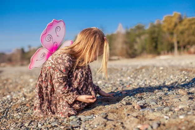 Entzückendes kleines Mädchen, das auf dem Strand an einem sonnigen Tag des Winters spielt