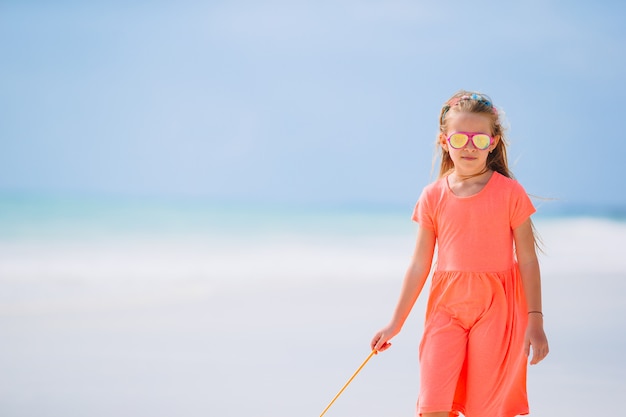 Entzückendes kleines Mädchen, das auf dem Strand geht