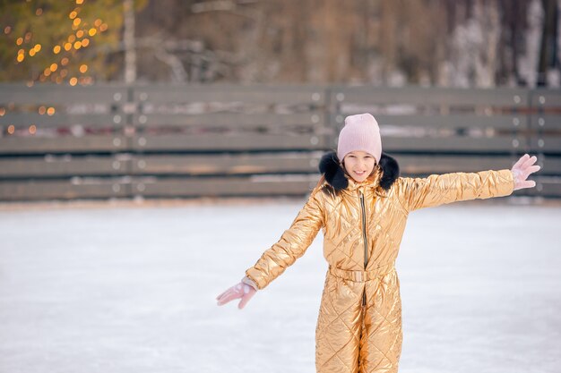 Entzückendes kleines Mädchen, das auf die Eisbahn eisläuft