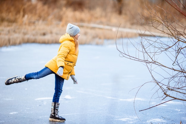 Entzückendes kleines Mädchen, das auf die Eisbahn eisläuft