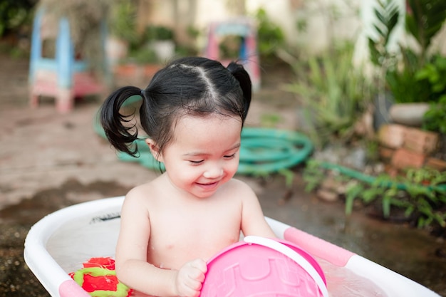 Entzückendes kleines Mädchen, das in der weißen Wanne ein Bad nimmt und Spielzeug spielt. Draufsicht auf ein kleines süßes Baby, das ein Bad nimmt und eine Duschzeit hat. Glückliches Kind im Badezimmer. Bild eines hübschen kleinen Mädchens im Gesundheitswesen