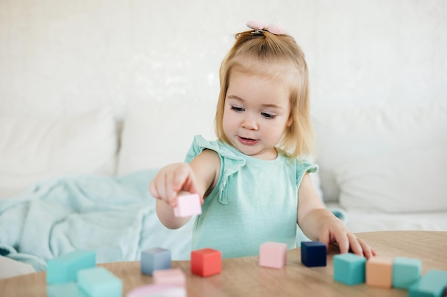 Entzückendes kleines Mädchen, das mit bunten Holzwürfeln spielt